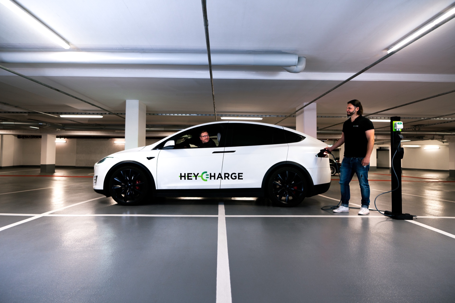 I fondatori di HeyCharge mentre ricaricano una Tesla in un garage dotato di HeyCharge